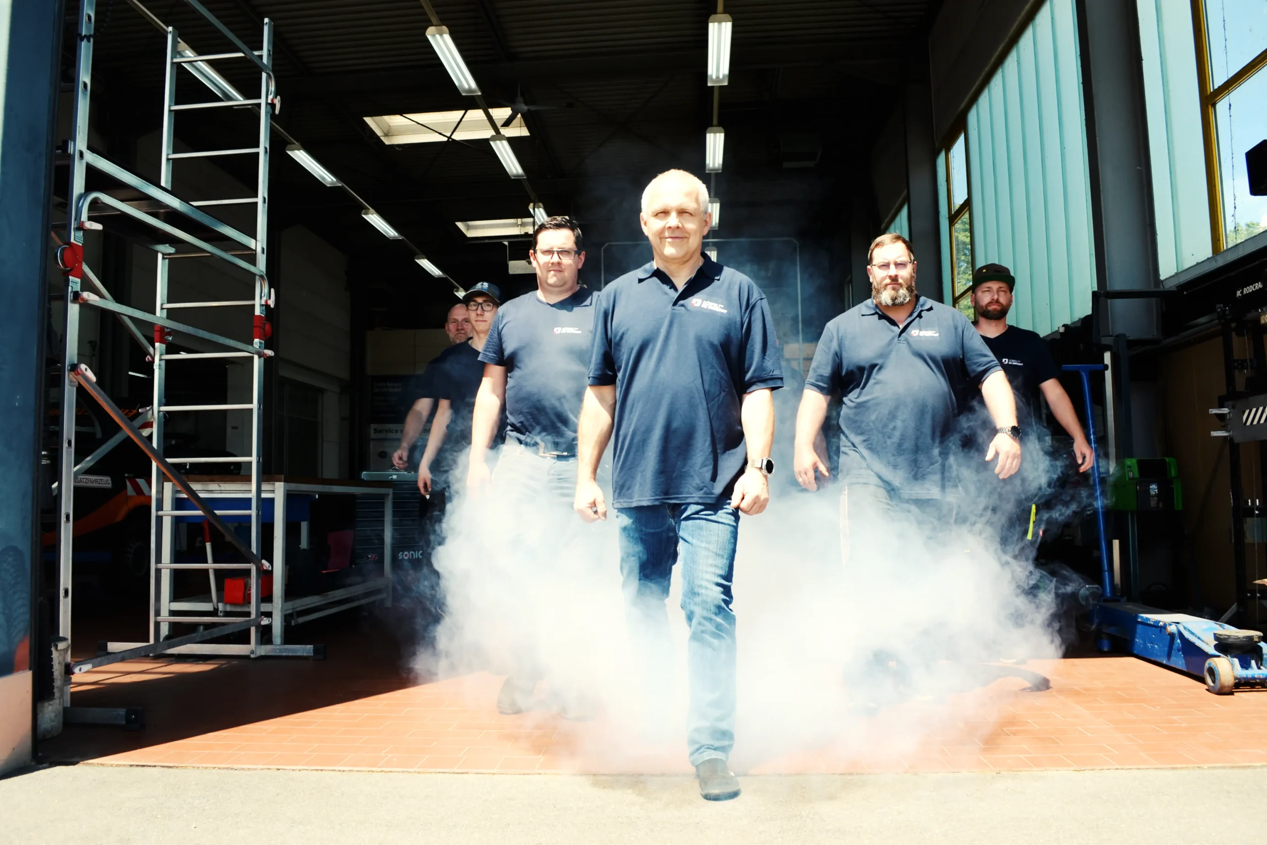 Team von DÖRFELT - DIE WERKSTATT in Zwickau läuft gemeinsam durch den Nebel und steht für Zusammenhalt Kompetenz und Leidenschaft erfahrene Kfz Meister Mechaniker Mechatroniker und Auszubildende bieten professionellen Werkstattservice Fahrzeugreparatur Nachrüstung und persönliche Beratung für Auto Wohnmobil und Nutzfahrzeuge